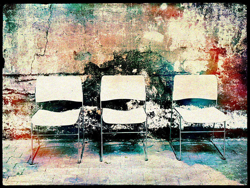 Drei Stühle vor verwitterter Wand | Dieses Fotokunstwerk fängt die stille Schönheit des Verfalls und die Schlichtheit alltäglicher Objekte ein. Drei weiße Stühle stehen gleichmäßig nebeneinander vor einer zerfallenen, farbenfrohen Wand – eine perfekte Verschmelzung von urbanem Charme und minimalistischer Ästhetik. Die raue Textur der Mauer im Kontrast zur glatten Oberfläche der Stühle erzählt von Geschichte und Gegenwart, von Vergänglichkeit und Ruhe. Ideal für moderne Wohn- oder Büroräume, die eine inspirierende Atmosphäre schaffen wollen - Realisiert mit Pictrs.com