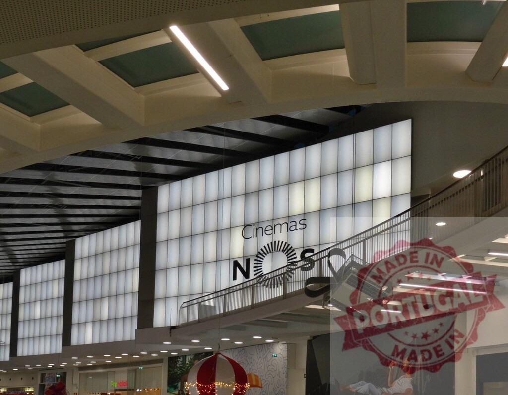 NOS Cinemas sign glowing in modern shopping mall interior | NOS Cinemas sign illuminating a contemporary commercial shopping mall interior with architecture - Realized with Pictrs.com