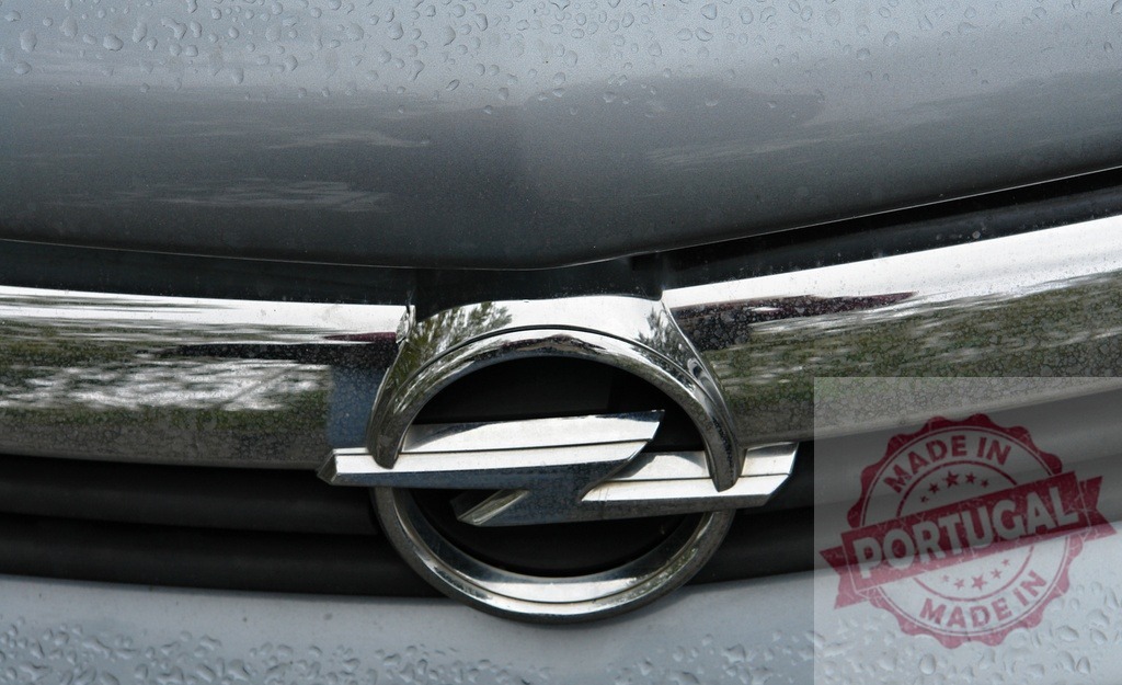 Opel car logo on wet vehicle grille after rain | Opel car emblem on a silver vehicle grille covered in water drops - Realized with Pictrs.com