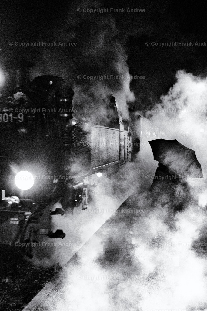 Abschied | Eine regnerische Nacht auf einem kleinen Bahnhof auf der Insel Rügen. Eine Dampflokomotive fährt aus dem Bahnhof. Auf dem Bahnsteig steht eine einzelne Frau mit Regenschirm inmitten des Qualms der alten Lokomotive und schaut dem abfahrenden Zug zu. Straßenfotografie in schwarz und weiß.
Ein melancholischer Moment des Abschieds auf einem Bahnsteig den ich fotografieren musste. - Realisiert mit Pictrs.com