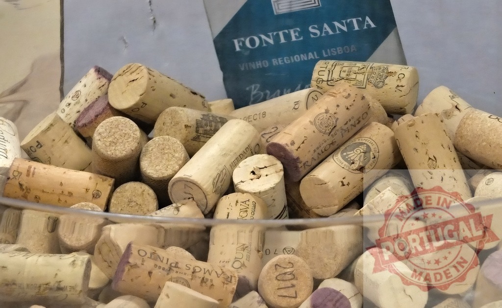 Cork collection displaying Portuguese wine brands Fonte Santa Ramos Pinto | Wine corks filling a glass bowl, showcasing various Portuguese labels and years - Realized with Pictrs.com