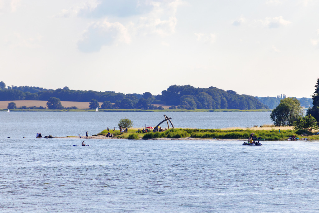 Wandbild: Blick von Lindaunis auf den Schleistrand Schneiderhaken | Dieses Wandbild im Querformat zeigt den Blick auf den Schleistrand Schneiderhaken von Lindaunis aus. Im Uferbereich ist ein Netzausleger zu sehen.  - Realisiert mit Pictrs.com