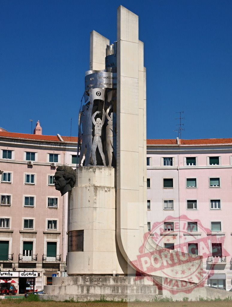 Largo do Rato monument celebrating democracy in Lisbon Portugal | Largo do Rato monument featuring figures and an abstract head against city buildings - Realized with Pictrs.com