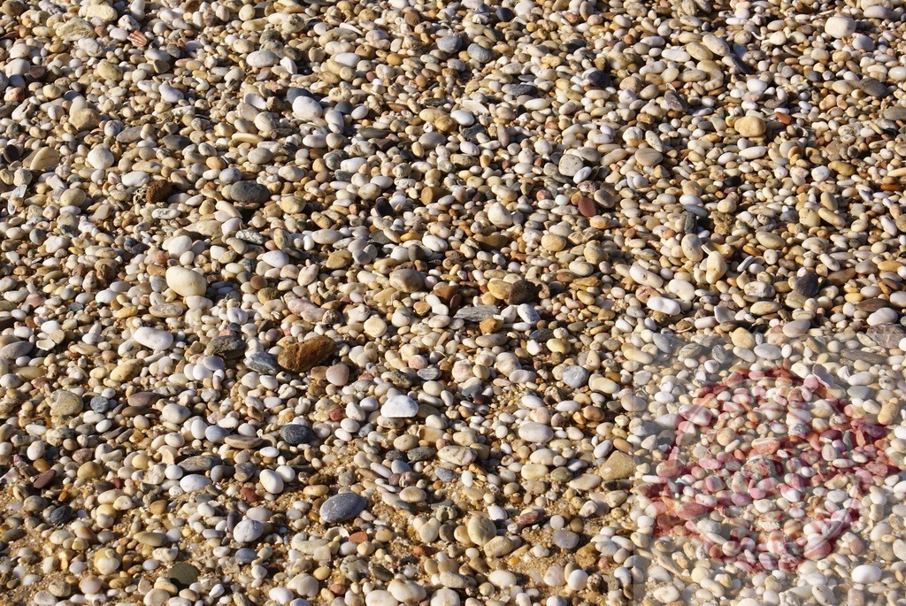 Small smooth beach pebbles creating natural texture background | Small rounded pebbles and grains of sand forming a textured natural surface - Realized with Pictrs.com