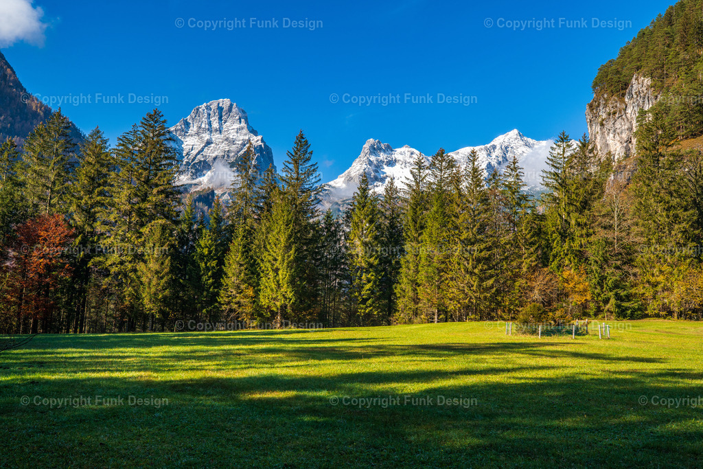 Bergpanorama am Schiederweiher – Hinterstoder, Oberösterreich, Österreich | Der Blick vom Schiederweiher öffnet sich auf ein beeindruckendes Bergpanorama mit frisch verschneiten Gipfeln und tiefgrünem Wald. Die sonnige Wiese im Vordergrund bringt Ruhe und Weite in das Motiv und macht es ideal als Naturbild für Wohn- oder Arbeitsräume.