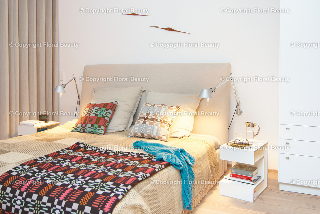 Schlafzimmer mit Raumteiler | Bett mit beiger Tagesdecke, Nachttischchen und Designerlampen - Realized with Pictrs.com