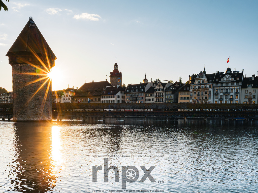 Kapellbrücke und Wasserturm Luzern im Abendlicht | Die tief stehende Sonne bricht sternförmig hinter dem Wasserturm hervor und taucht die Kapellbrücke sowie die Altstadt von Luzern in warmes Abendlicht.  - Realisiert mit Pictrs.com