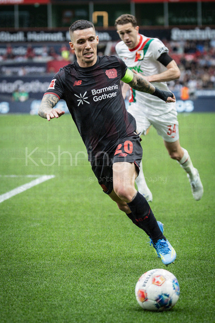 German Bundesliga, Bayer 04 Leverkusen vs. FC Augsburg, 18.04.2026 | LEVERKUSEN, GERMANY - APRIL 18, 2026 :  Alejandro Grimaldo (Bayer 04 Leverkusen, 20), Arthur Chaves (FC Augsburg, 34) during the German Bundesliga match on gameday 30 between Bayer 04 Leverkusen vs. FC Augsburg at BayArena on April 18, 2026 in Leverkusen, Germany. DFL REGULATIONS PROHIBIT ANY USE OF PHOTOGRAPHS AS IMAGE SEQUENCES AND/OR QUASI-VIDEO.