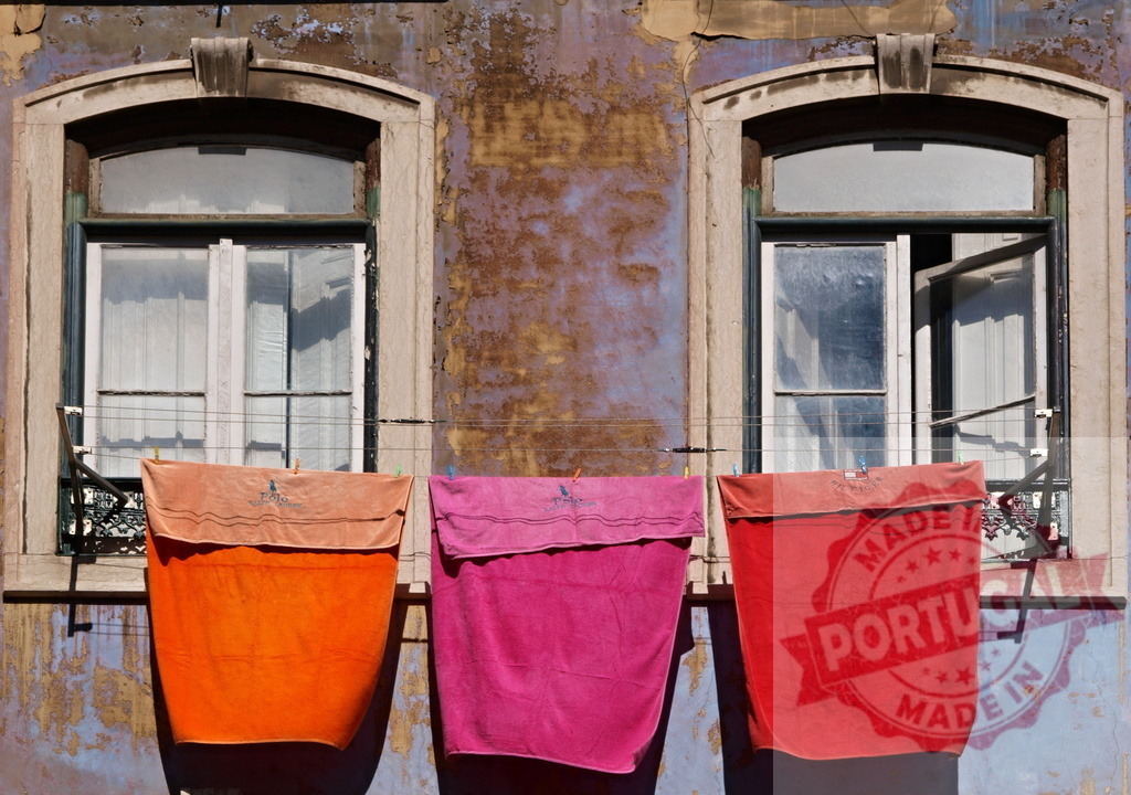 Colorful towels drying on clothesline in old building windows. Lisbon - Portugal | Bright towels hanging on a clothesline in front of weathered building windows, showcasing urban life - Realisiert mit Pictrs.com