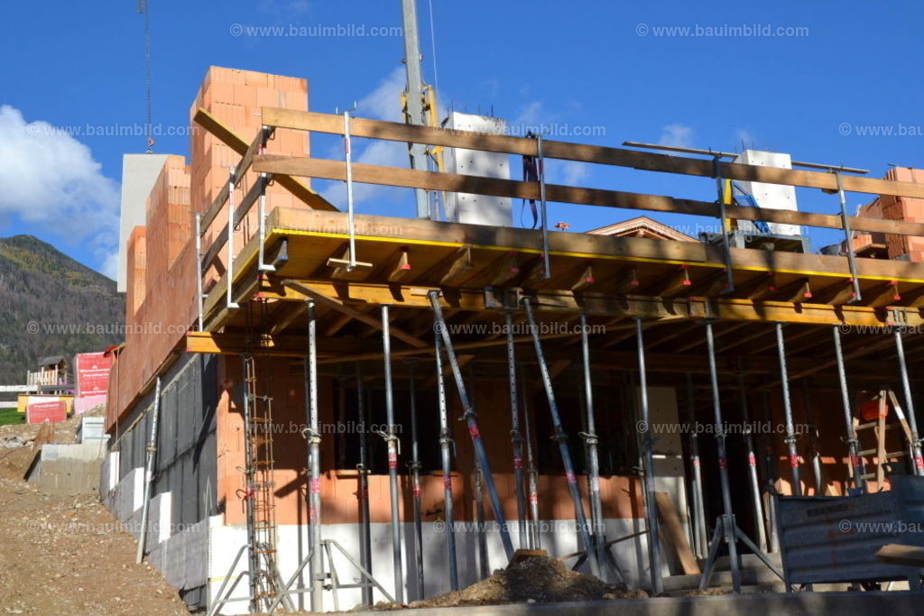 Schalung Balkonplatte Massivhaus | Geschalte Balkonplatte mit Unterstellung und Schutzgerüst bei Ziegel-Massivhaus, Hintergrund blauer Himmel  