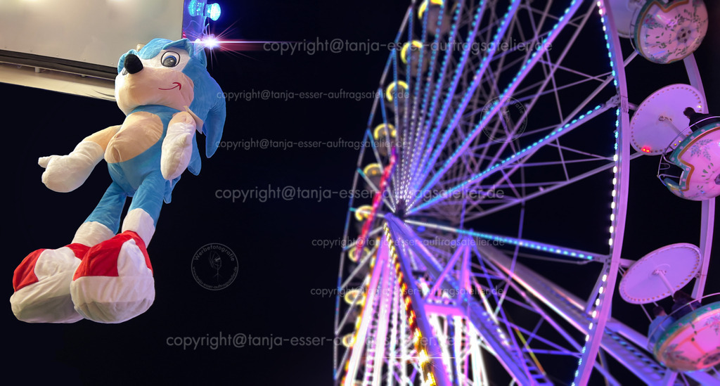 Kirmes Brilon Plüschtiere an der Losbude Abends | Brilon, Nord Rhein Westfalen/Deutschland - September 24th, 2023: Beleuchtetes Riesenrad und Plüschtier Sonic the Hedgehog. Das Spielzeug hängt an einer Losbude. Schönes Bokeh.