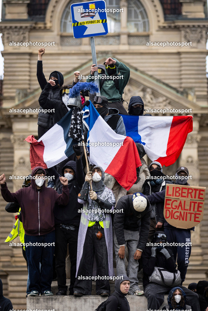 _B7A6611 | Strasbourg, France, 24 octobre 2026. Des manifestants affrontent les forces de l’ordre lors d’une mobilisation dans le centre-ville de Strasbourg. Des policiers interviennent pour disperser des groupes de manifestants, tandis que des gaz lacrymogènes sont utilisés. Des affrontements, des jets de projectiles et des dégradations sont observés dans plusieurs rues. Des barricades et des véhicules en feu témoignent de la tension qui règne en marge de la mobilisation. - Realisiert mit Pictrs.com