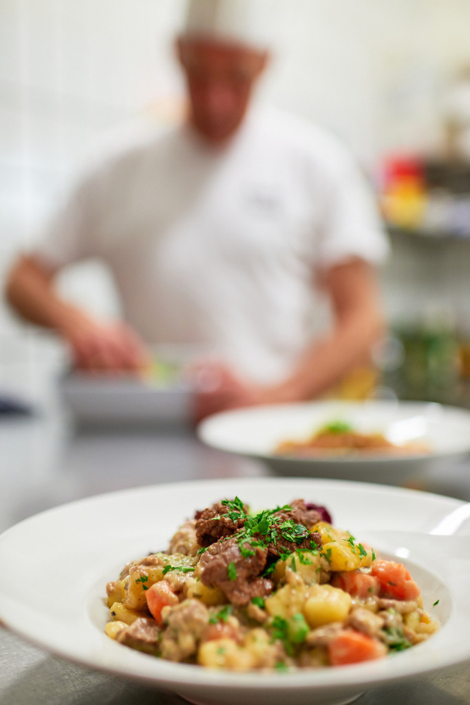 Cafe Sluka - Rindfleischeintopf mit Gemüse | Wien, Austria - March 28, 2018: Conditorei Sluka Rathausplatz; Rindfleischeintopf mit Gemüse im Teller angerichtet, im Hintergrund Küchenchef Josef Thury. - Realisiert mit Pictrs.com
