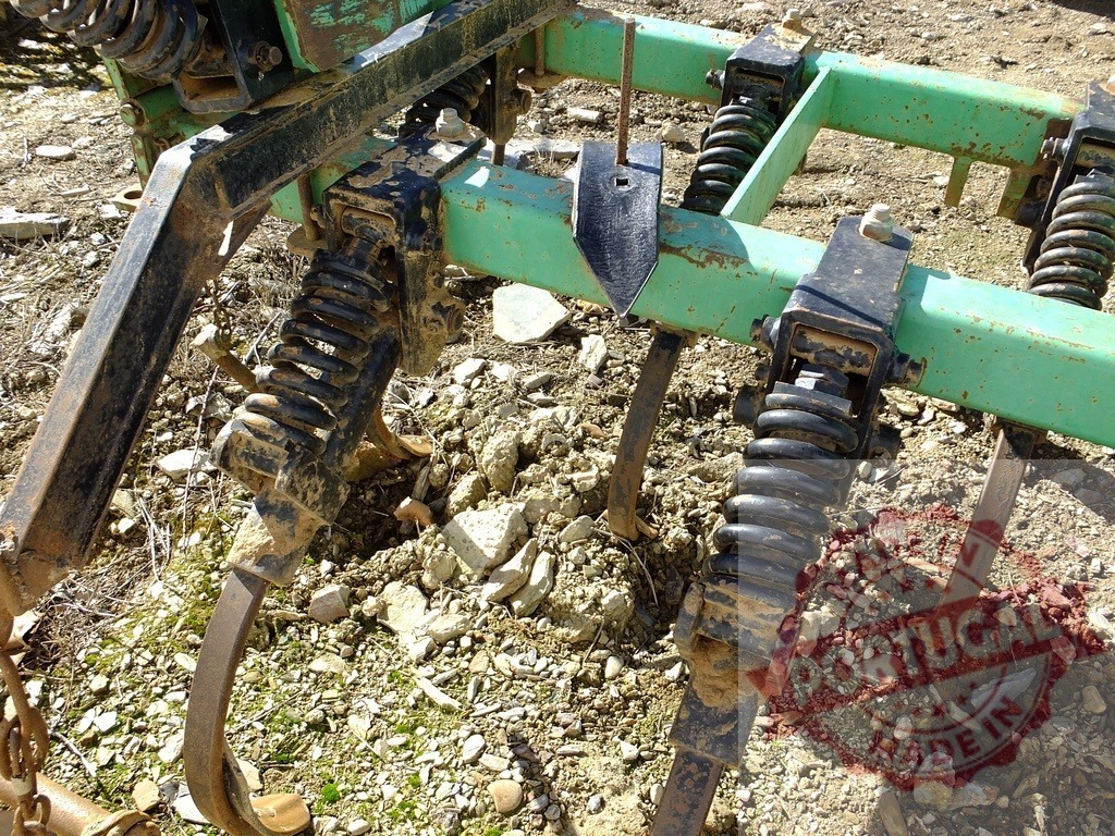 Agricultural cultivator preparing soil for farming season | Cultivator mechanism showing springs and tines for tilling the land - Realized with Pictrs.com