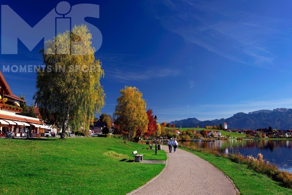 2.Liga-1860-HEIM.jpg | 17.10.2022, Herbst am Hopfensee im Allgäu (Bayern) bei Füssen. Bei sommerlichen Temperaturen geniessen viele Ausflügler die herbstliche Landschaft am See. Hier die Promenade in Hopfen am See. - Realisiert mit Pictrs.com