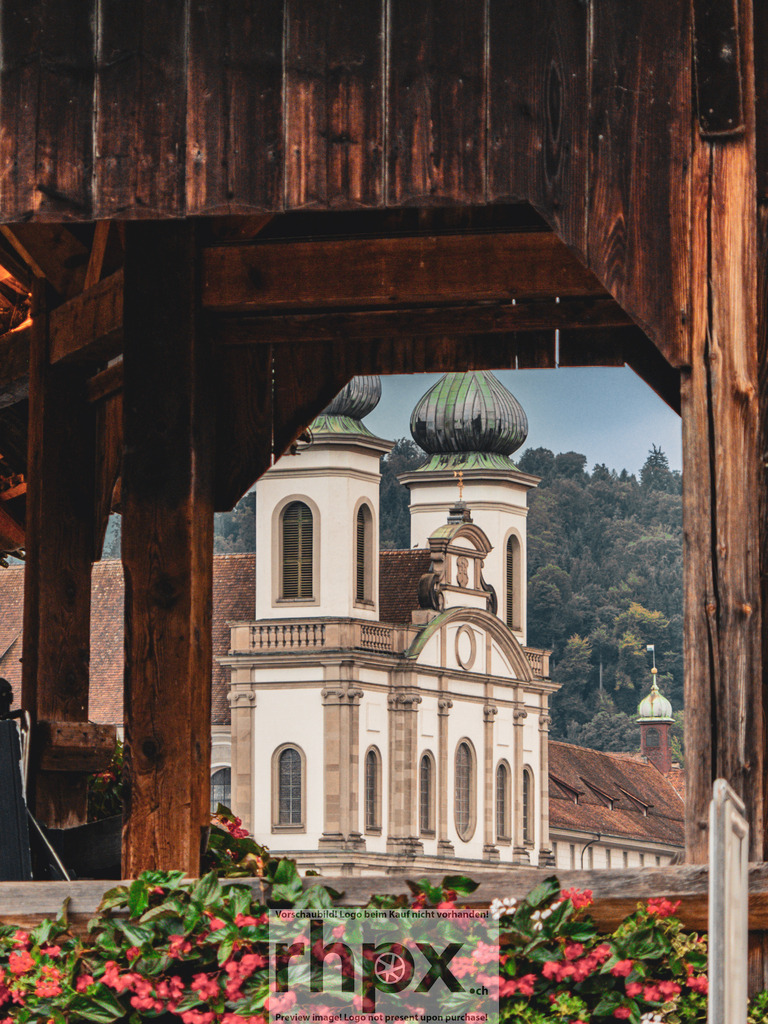 Blick auf die Jesuitenkirche Luzern | Barock. Holz. Perspektive.Ein klassischer Blick auf die prachtvolle Jesuitenkirche, eingerahmt durch die rustikale Holzstruktur der historischen Kapellbrücke. Das Zusammenspiel von sakraler Architektur und dem warmen Holz schafft eine zeitlose Komposition voller Tiefe.Wähle unter "Produktauswahl" dein Wunschformat: Vom klassischen Wandbild über Puzzle &amp; Tassen bis zum digitalen Download (z.B. als Handy-Hintergrund). - Realisiert mit Pictrs.com