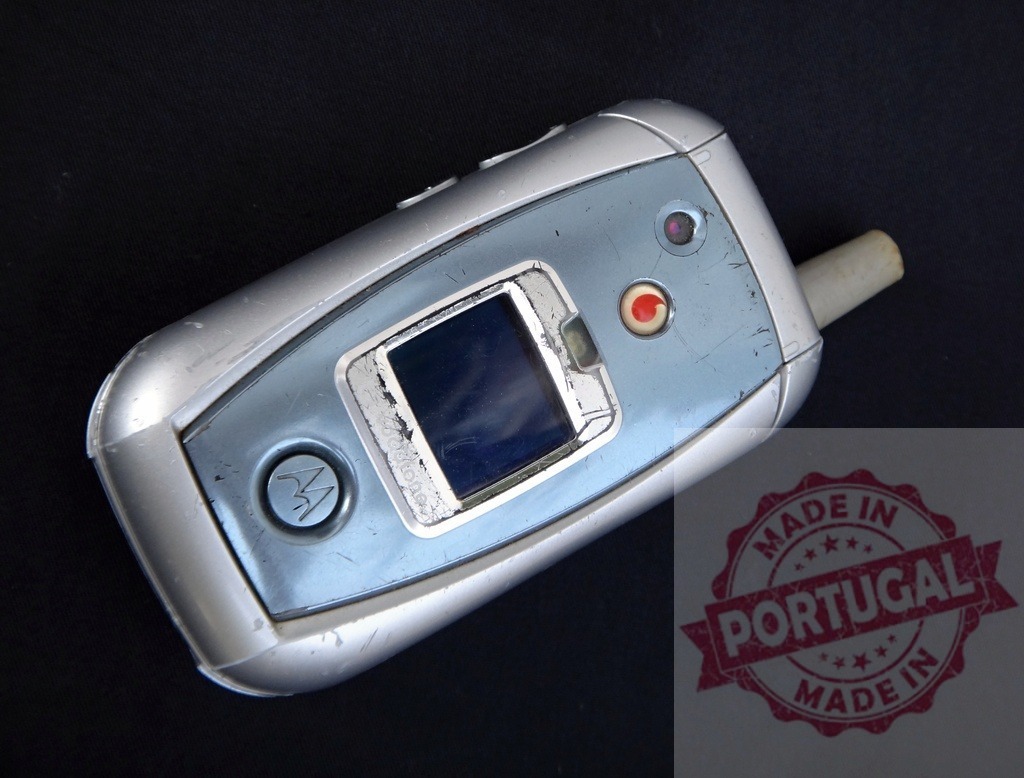 Old used Motorola flip phone showing signs of wear and tear | Scratched and worn blue Motorola V3 Razr flip phone on a black background, showcasing its age and use - Realisiert mit Pictrs.com