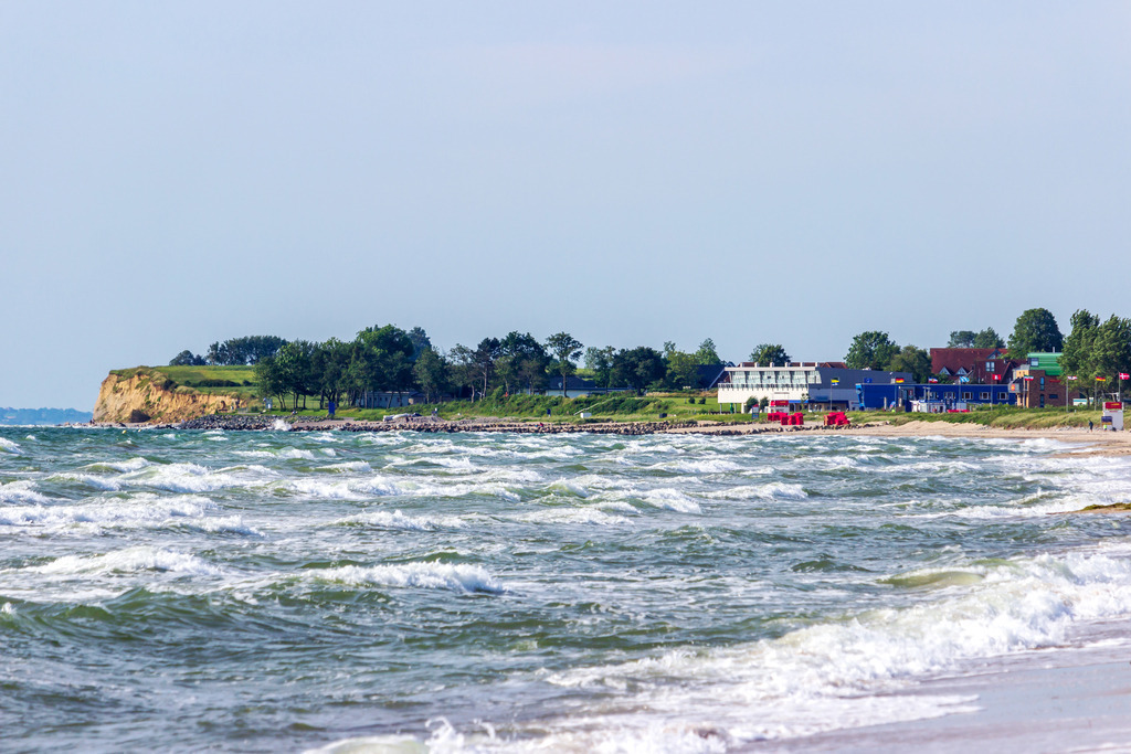 Steilküste & Strand – maritime Eleganz für Zuhause | Vom Weidefelder Strand aus öffnet sich der Blick entlang der Küste bis zum benachbarten Strand und der Steilküste von Schönhagen. Die Wellen der Ostsee brechen gleichmäßig ans Ufer, begleitet vom stetigen Klang des Wassers und einer frischen Brise. Die Küstenlinie mit ihren grünen Hängen und der weite Horizont verleihen dem Motiv eine Mischung aus Kraft und Gelassenheit. Dieses Wandbild bringt die raue Schönheit der Ostseeküste direkt ins Zuhause und lädt dazu ein, für einen Moment innezuhalten und durchzuatmen. - Realisiert mit Pictrs.com