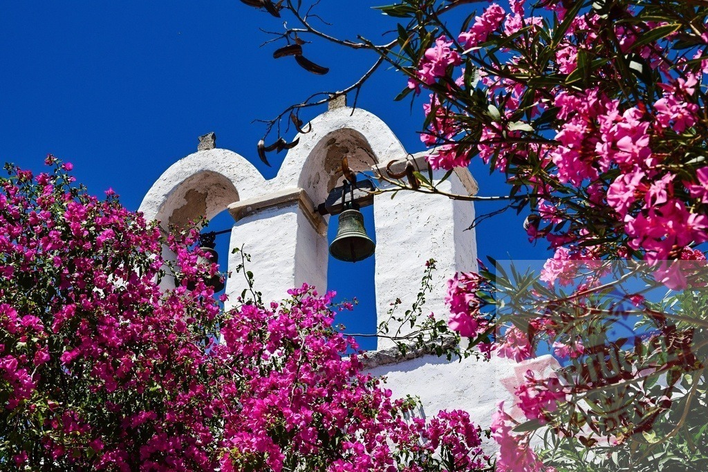 Greece church bell among vibrant bougainvillea flowers | White church bell tower surrounded by bright pink bougainvillea under a clear blue sky - Realisiert mit Pictrs.com