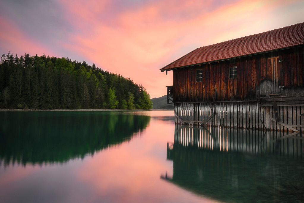 Spiegelglanz am Walchensee  | Sanfte Farben spiegeln sich im glasklaren Wasser, die Linien der Hütte führen den Blick in die Tiefe der Szene. Der Walchensee zeigt sich in diesen Momenten von seiner stillsten Seite. - Realisiert mit Pictrs.com