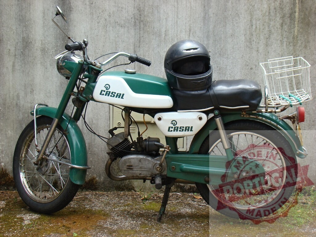 Green and white CASAL moped parked by a wall, complete with a helmet and basket, evoking a sense of nostalgia | Vintage CASAL moped parked against a weathered wall, showcasing classic two-wheeler design with helmet and basket - Realized with Pictrs.com