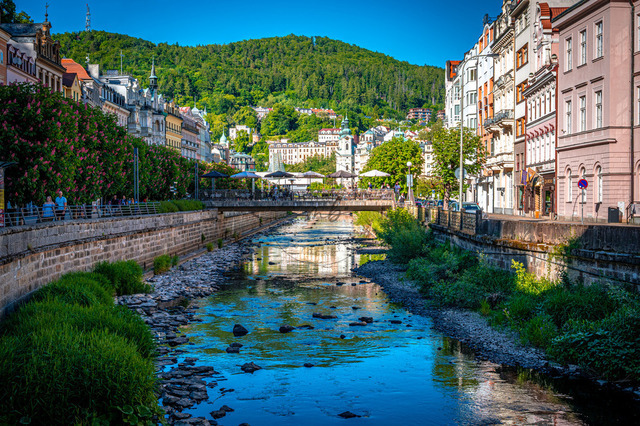 In Karlsbad fließt ein Fluss durch die Stadt. Alte Häuser stehen am Ufer. Bäume und Pflanzen wachsen entlang des Wassers. Menschen besuchen die Gegend | In Karlsbad fließt ein Fluss durch die Stadt. Alte Häuser stehen am Ufer. Bäume und Pflanzen wachsen entlang des Wassers. Menschen besuchen die Gegend. - Realisiert mit Pictrs.com