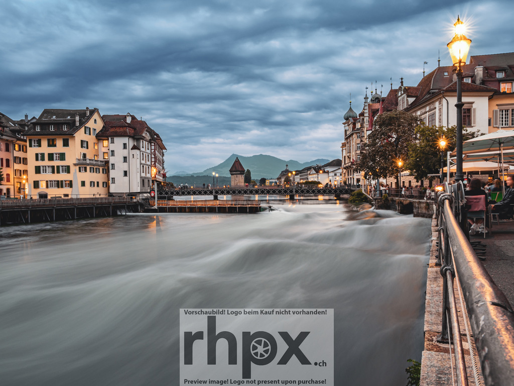 Reuss Luzern – Blick auf die Altstadt | Langzeitaufnahme der Reuss mit Blick auf die Luzerner Altstadt. Die ruhige Wasseroberfläche und das warme Licht der Strassenlaternen zeigen den Übergang vom Tag zur Nacht. - Realisiert mit Pictrs.com