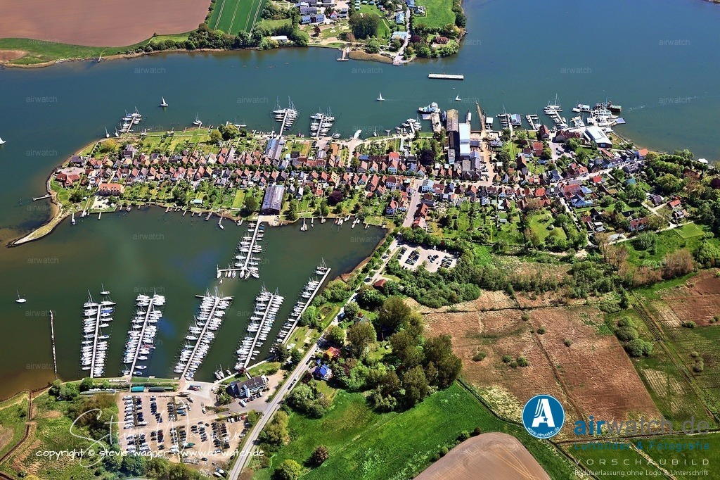 Luftbild Stadt Arnis - Gesäumt von alten Linden am Ostseefjord Schlei | Stadt Arnis: Die Lange Straße ist die Hauptachse von Arnis und erstreckt sich von einem Ende der Stadt zum anderen. Gesäumt von alten Linden und geprägt von bunten, blumenreichen Fachwerkhäusern, bietet sie ein besonders malerisches Bild, besonders im Sommer, wenn die Blumenpracht in voller Pracht steht. Auffällig sind die „Utluchten“ – kleine Anbauten über der Fassade, die es den Bewohnern früher ermöglichten, das Treiben auf der Straße zu beobachten. Die Straße vermittelt den Charme einer vergangenen Zeit und lädt zum Flanieren und Fotografieren ein.
