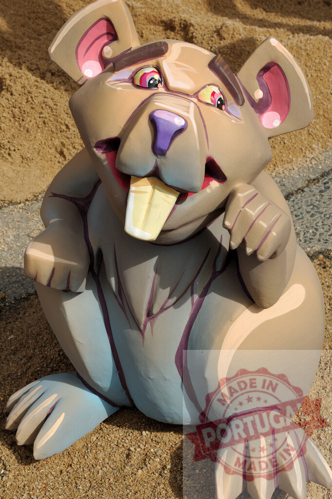 Cartoon rat sculpture sitting on sandy ground. Fallas Fiestas Communidad Valenciana | Cartoon rat sculpture with big teeth and ears sitting on sandy ground - Realized with Pictrs.com