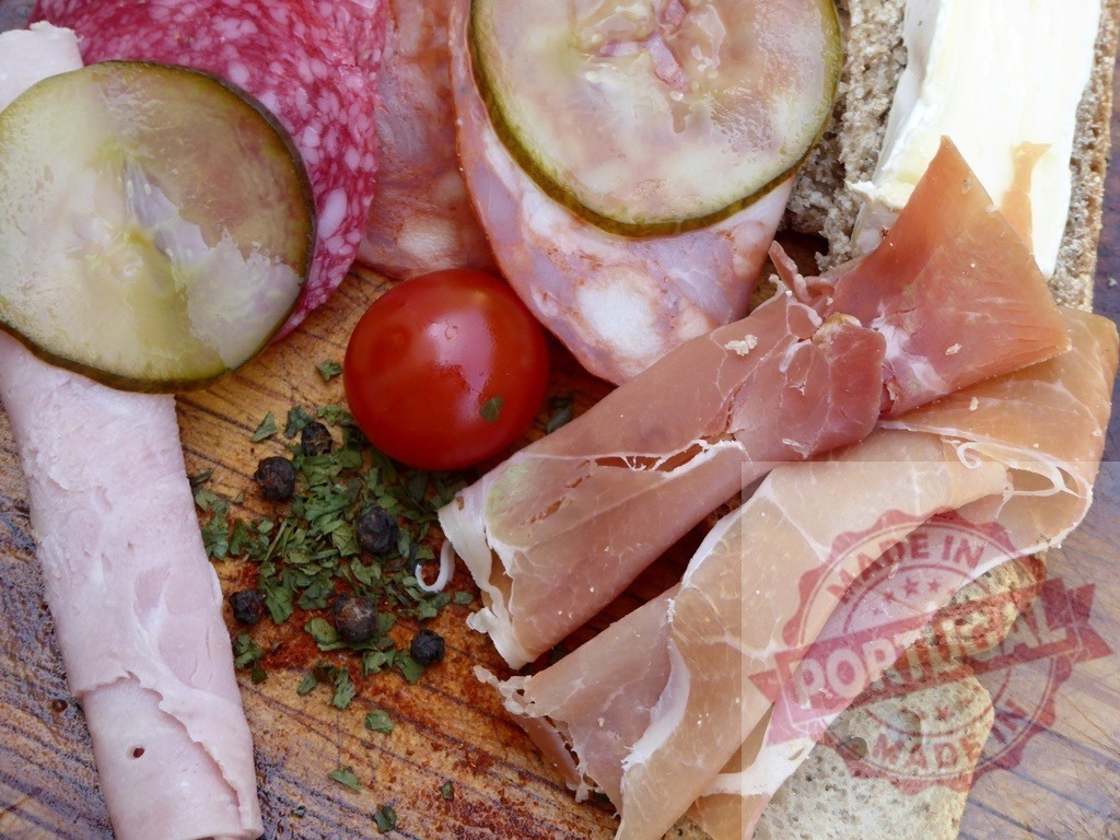 Charcuterie board with assorted cured meats and pickles | Assorted cured meats, pickles, cheese, and vegetables arranged on a rustic wooden board - Realized with Pictrs.com