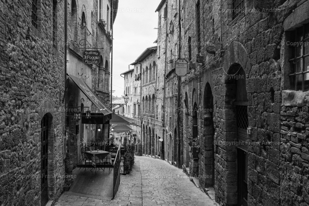 Straße in Volterra Toskana | Schwarz weiß Fotografie einer engen menschenleeren Straße in der bezaubernden Altstadt von Volterra in der Toskana. Blick entlang der alten Häuser. - Realisiert mit Pictrs.com