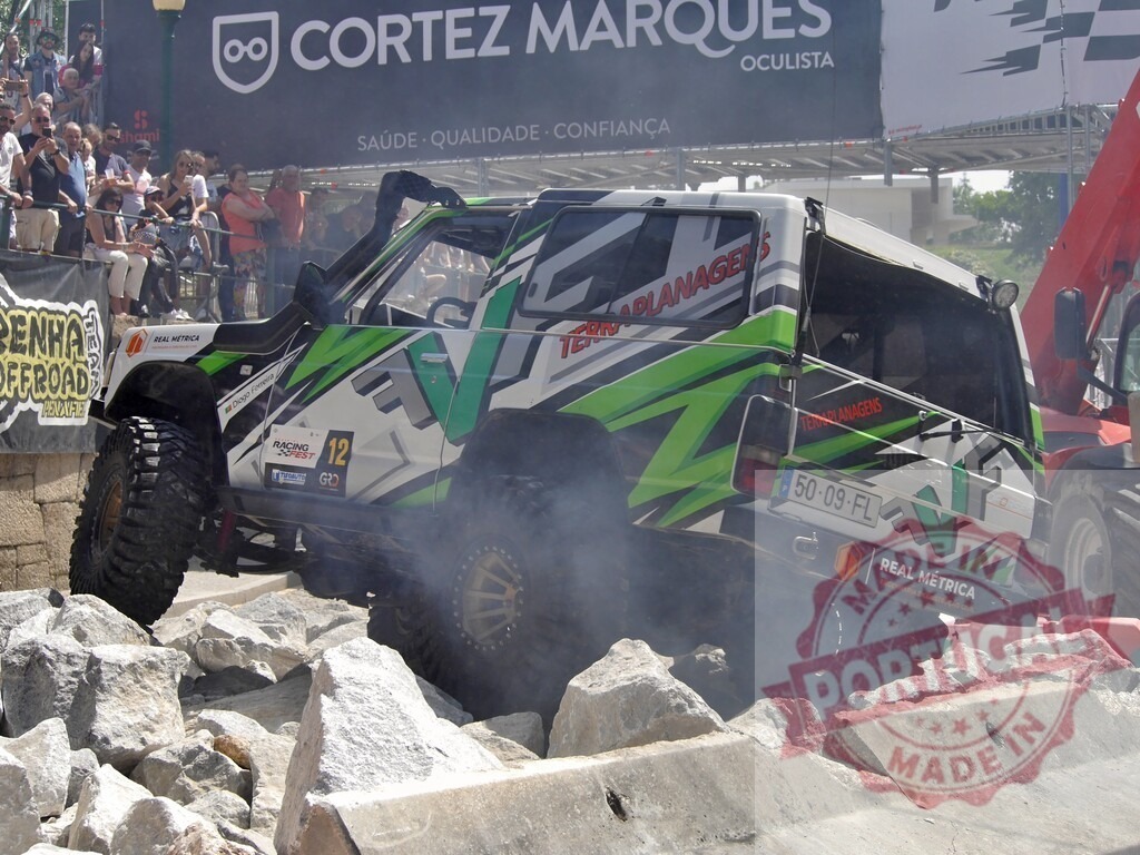 Nissan Patrol competing in an offroad race, climbing rocks in front of spectators | Modified Nissan Patrol climbing rocks during an offroad competition, watched by spectators - Realized with Pictrs.com