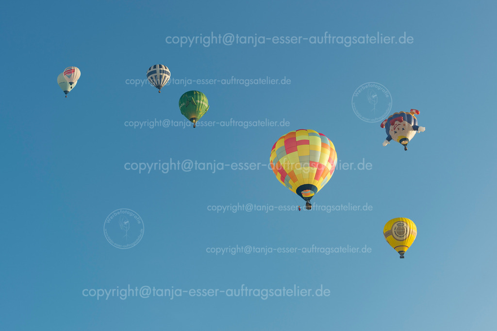 Heißluftballons nah und fern erkennt man nur an der Größe im blauen Himmel | Start der Heißluftballone in Oeventrop/Arnsberg im Morgennebel. Die Warsteiner Internationale Montgolfiade ist der Veranstalter. Verschiedene Formen von Ballons.