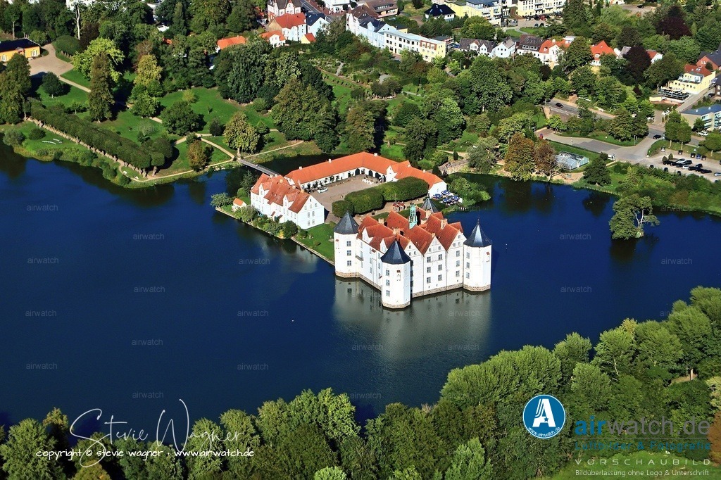 Luftbild Schloss Glücksburg - Der Bau kostete damals umgerechnet 1.200 Rindviecher oder 6.000 lübische Mark | Dabei wurden viele Baumaterialien des alten Klosters, wie Granitquader und Ziegelsteine, wiederverwertet. Der Bau kostete damals umgerechnet 1.200 Rindviecher oder 6.000 lübische Mark. Das Schloss ist ein quadratisches Gebäude mit einer Kantenlänge von je 30 Metern, umgeben von vier achteckigen Türmen mit einem Durchmesser von jeweils 7 Metern und steht auf einem 2,5 Meter hohen Granitsockel.