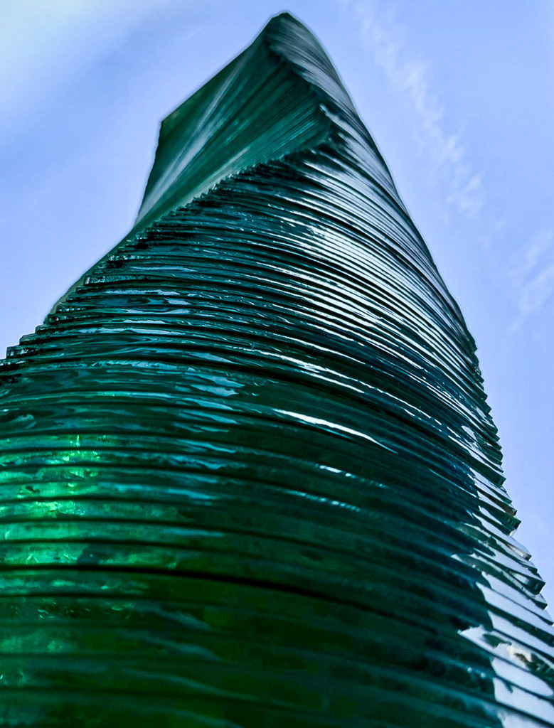 Grüner Glasturm Lörrach | Abstract Glass Architecture | Abstrakte Architekturfotografie eines futuristischen Glasturms in Lörrach. Die geschichteten grünen Glasplatten bilden eine dynamische, organische Skulptur vor strahlend blauem Himmel. Perfekt als moderne Wandkunst für anspruchsvolle Wohnräume und Büros. / Abstract green glass tower structure. - Realisiert mit Pictrs.com