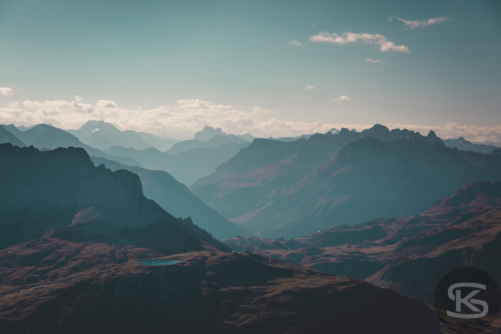 Blick vom Großen Widderstein Richtung Tirol - Alpenpanorama Vorarlberg | Spektakuläres Bergpanorama vom Gipfel des Großen Widdersteins mit Blick nach Tirol. Majestätische Alpenketten in atmosphärischen Dunstschichten, dramatische Gebirgszüge und weite Täler vereinen sich zu einem eindrucksvollen Weitblick über die Alpen. - Realisiert mit Pictrs.com