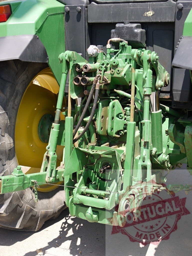 Green tractor rear hydraulic linkage mechanism close up | Agricultural tractor rear three-point hitch system engaging farming implements - Realized with Pictrs.com
