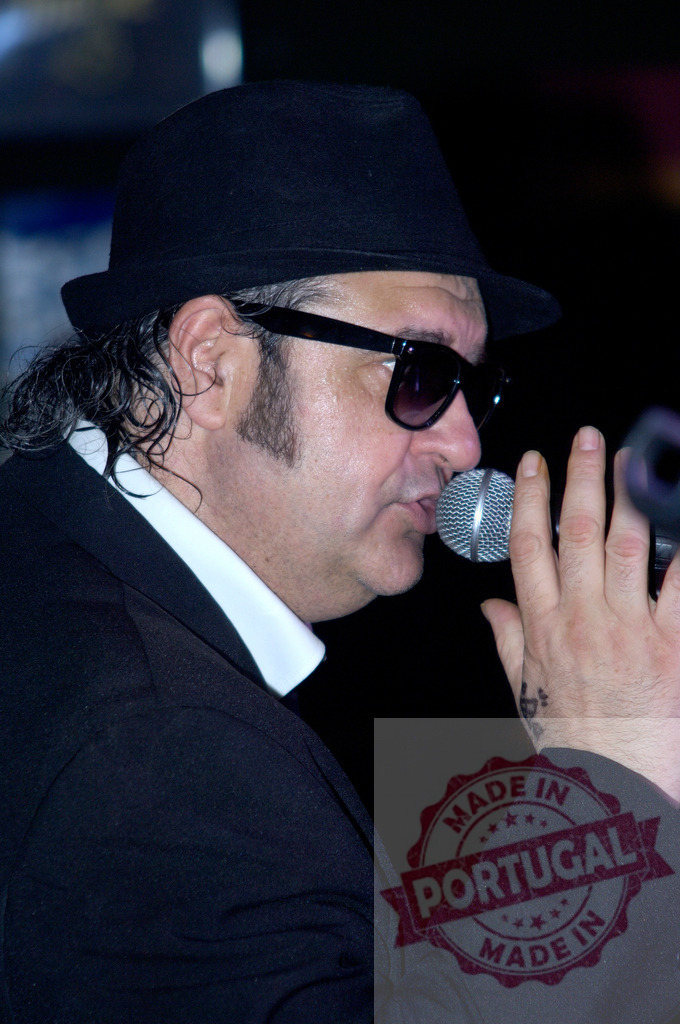 Singer performing live music with microphone and sunglasses | Male singer is singing with passion and style on a stage, using a microphone and wearing sunglasses - Realisiert mit Pictrs.com