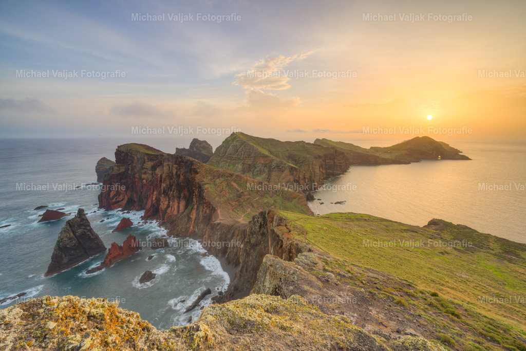 Ponta de São Lourenço bei Sonnenaufgang | Ponta de São Lourenço auf Madeira bei Sonnenaufgang ist ein beeindruckender Anblick. Die ersten Sonnenstrahlen beleuchten die Felsen und die Küstenlinie in warmem Licht. Der Himmel zeigt sanfte Farben von Blau, Orange und Gelb, während das blaue Wasser des Atlantiks gegen die Klippen schlägt. Die Halbinsel erstreckt sich ins Meer, umgeben von unberührter Natur, die im Morgengrauen erwacht. Die Landschaft, geprägt von Felsen und karger Vegetation, bietet ein Gefühl von Ruhe und Erhabenheit. Es ist ein Moment der Schönheit und Stille, der den Betrachter in seinen Bann zieht. - Realisiert mit Pictrs.com