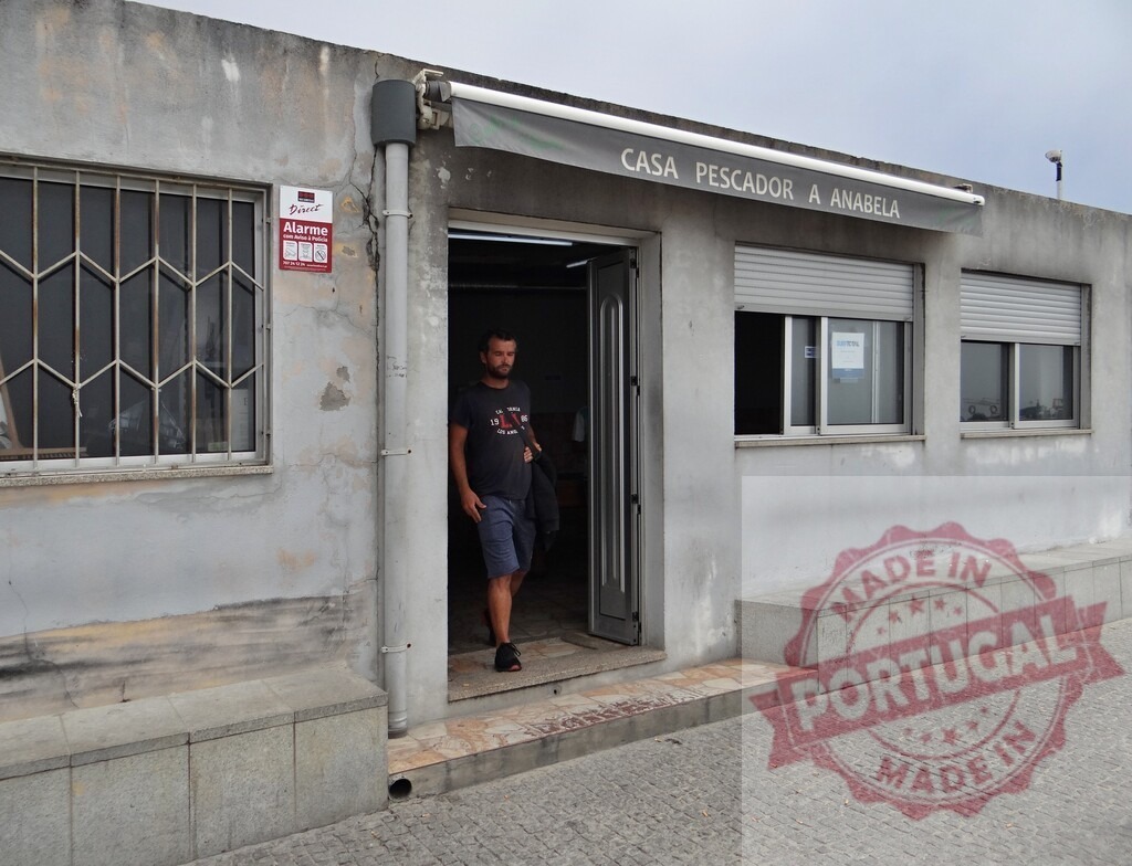 Man entering a traditional Portuguese building on a street | Man in casual clothing walking out of a traditional facade with CASA PESCADOR A ANABELA sign - Realisiert mit Pictrs.com