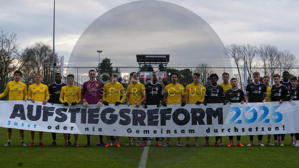 Fußball, Herren, Saison 2025/2026, Regionalliga Nordost, 18. Spieltag, FSV 63 Luckenwalde vs. FC Rot-Weiß Erfurt, Samstag 06.12.2025, Werner-Seelenbinder-Stadion Luckenwalde, | Fußball, Herren, Saison 2025/2026, Regionalliga Nordost, 18. Spieltag, FSV 63 Luckenwalde vs. FC Rot-Weiß Erfurt, Samstag 06.12.2025, Werner-Seelenbinder-Stadion Luckenwalde, Im Bild: Beide Mannschaften halten ein Banner zur Aufstiegsreform 2025 - Realisiert mit Pictrs.com