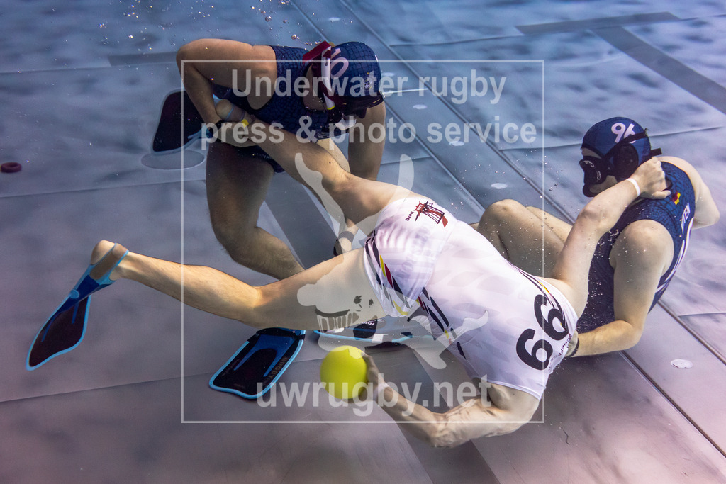 Deutsche Meisterschaft 2024 in Unterwasser-Rugby | Vorrundenspiel: Tauchclub Bamberg in weiß gegen DUC Krefeld in blau. Der Bamberger  Spieler David Scheffczyk (Nummer 99) setzt sich gegen zwei Krefelder Spieler mit dem Ball durch. - Realisiert mit Pictrs.com