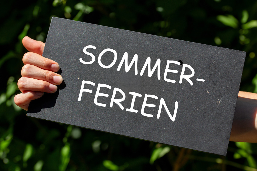 Symbolbild Sommerferien: Schüler hebt ein Schild mit der Aufschrift SOMMERFERIEN in der Hand | Symbolbild Sommerferien: Schüler hebt ein Schild mit der Aufschrift SOMMERFERIEN in der Hand - Realisiert mit Pictrs.com
