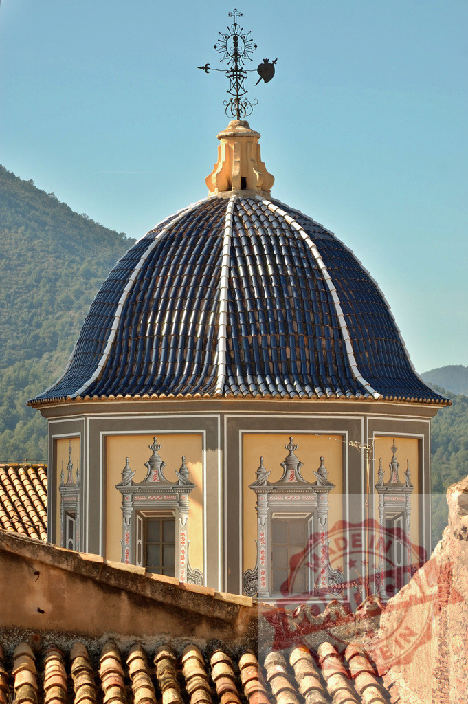 Eslida church dome with traditional blue tiles and weather vane in Spain. Cuenca - Spain | Ornate church dome featuring blue tiles and a decorative weather vane against a clear sky - Realized with Pictrs.com