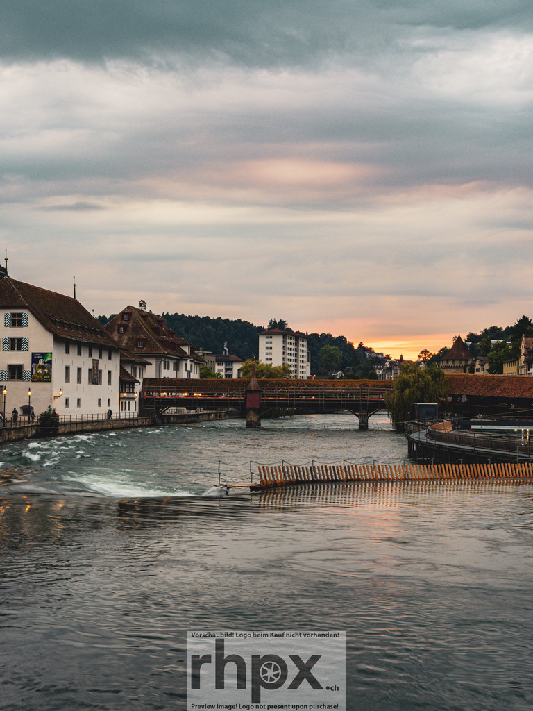 Nadelwehr Luzern | <p><strong>Tradition. Technik. Fluss.</strong></p><p>Das Nadelwehr in der Reuss ist ein Meisterwerk der Mechanik, das seit Generationen das Stadtbild von Luzern prägt. Die Aufnahme fängt die fliessende Energie des Wassers und die markante Silhouette der Spreuerbrücke in der sanften Dämmerung ein.</p><p>Wähle unter "Produktauswahl" dein Wunschformat: Vom klassischen Wandbild über Puzzle & Tassen bis zum digitalen Download (z.B. als Handy-Hintergrund).</p><br> - Realisiert mit Pictrs.com