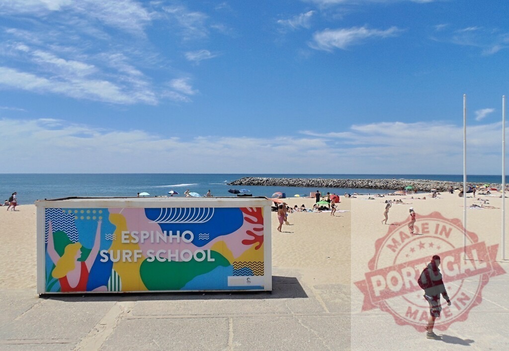 Espinho Surf School container on a sunny Portugal beach. Aveiro - Portugal | Colorful Espinho Surf School container on a busy sandy beach with people by the ocean - Realized with Pictrs.com