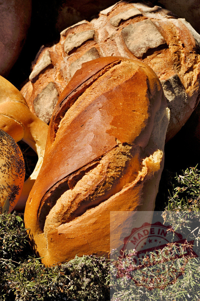 Artisan bread loaves, fresh baked crusty rustic food | Artisan bread loaves displaying crispy crusts and golden brown colors, presented with fresh herbs - Realized with Pictrs.com