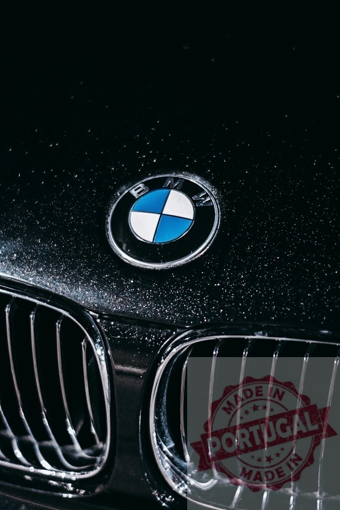 BMW logo shining on wet black luxury car with water drops | Close-up of BMW logo on a wet car after washing, showcasing luxury and automotive design - Realisiert mit Pictrs.com