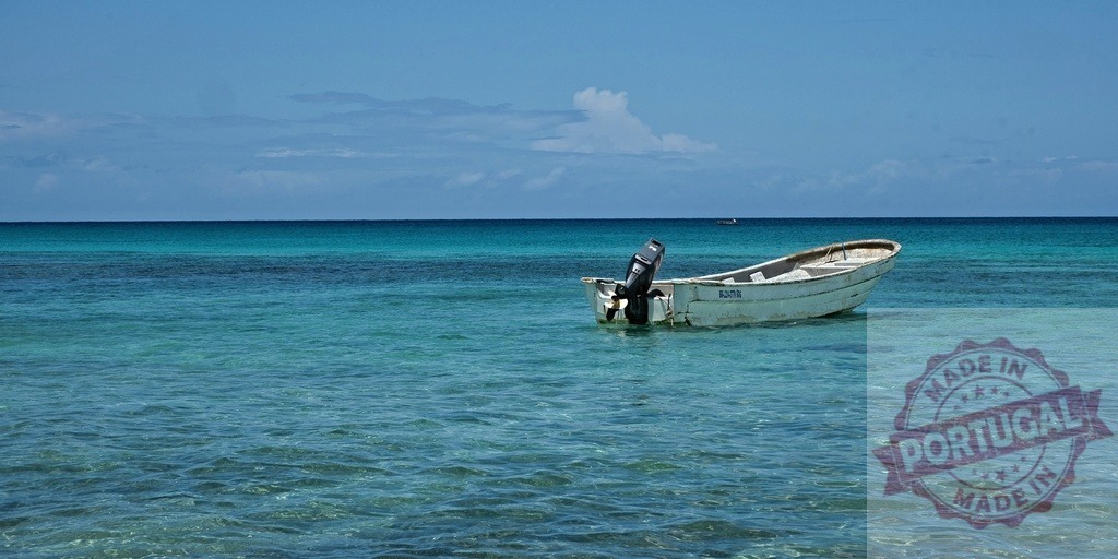 Small boat floating on clear turquoise tropical water | Small fishing boat moored in calm, clear turquoise ocean on a summer day - Realized with Pictrs.com