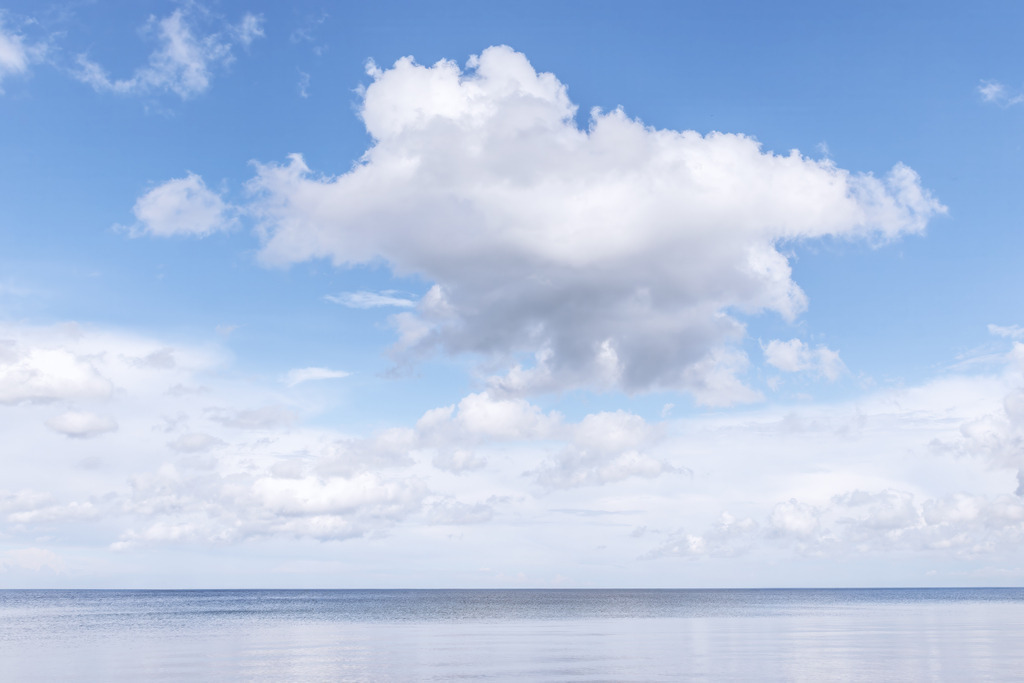 Majestätische Wolken über dem Meer – Edles maritimes Wandbild fürs Wohnzimmer | Dieses maritime Wandbild zeigt eine beeindruckende Wolkenformation über dem ruhigen Meer und fängt die stille, klare Atmosphäre eines friedlichen Küstenmoments ein. Die weite Wasserfläche und der helle Himmel erzeugen ein Gefühl von Freiheit, Leichtigkeit und natürlicher Harmonie. Das Bild setzt einen eleganten, zeitlosen Akzent in modernen und hellen Wohnräumen und bringt die beruhigende Wirkung des Meeres direkt an die Wand. Ideal für alle, die hochwertige Küstenmotive und eine entspannte maritime Stimmung schätzen.